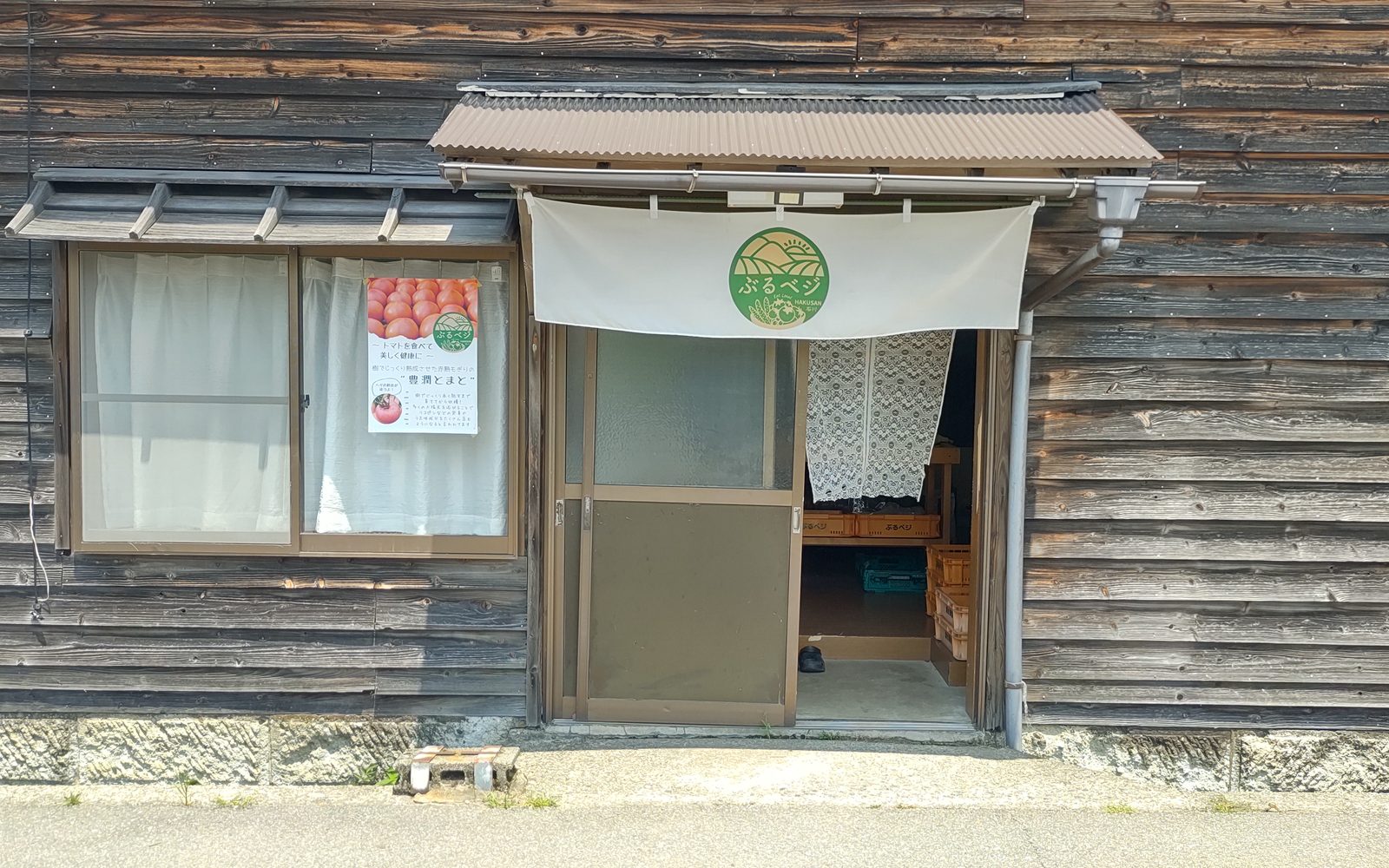 ぶるベジのロゴが入ったのれんが下がる、木造の直売所の入り口